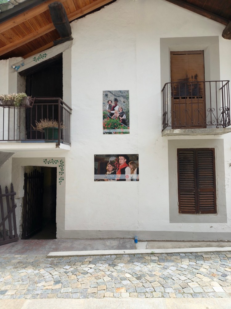 Facciata di una casa con due balconi, decorata con foto di persone in posa in giardino.