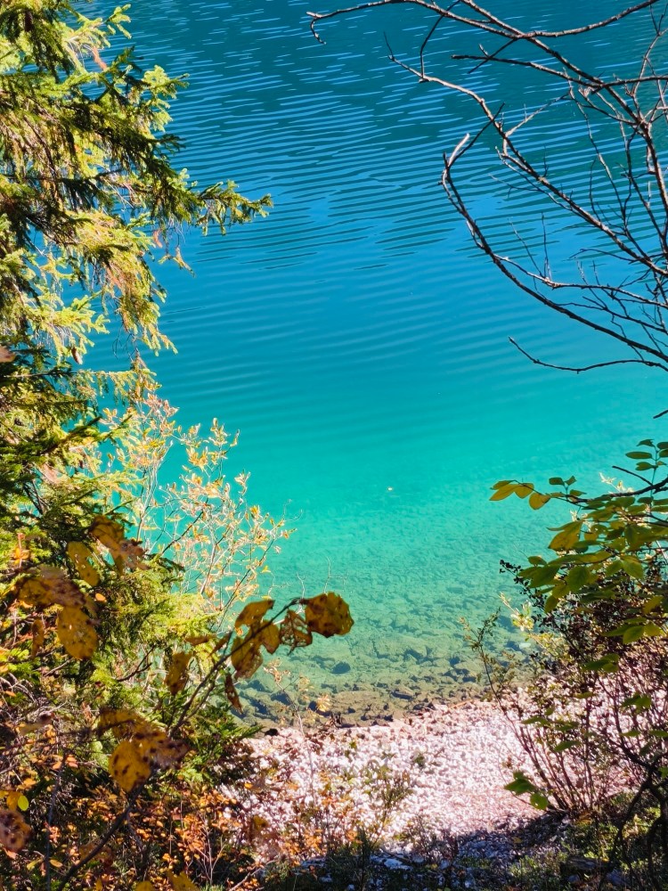 Vista sopraelevata di un lago con acque turchesi, circondato da vegetazione e rocce.