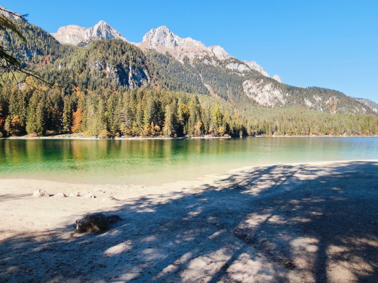Vista panoramica di un lago circondato da montagne e foreste in autunno.