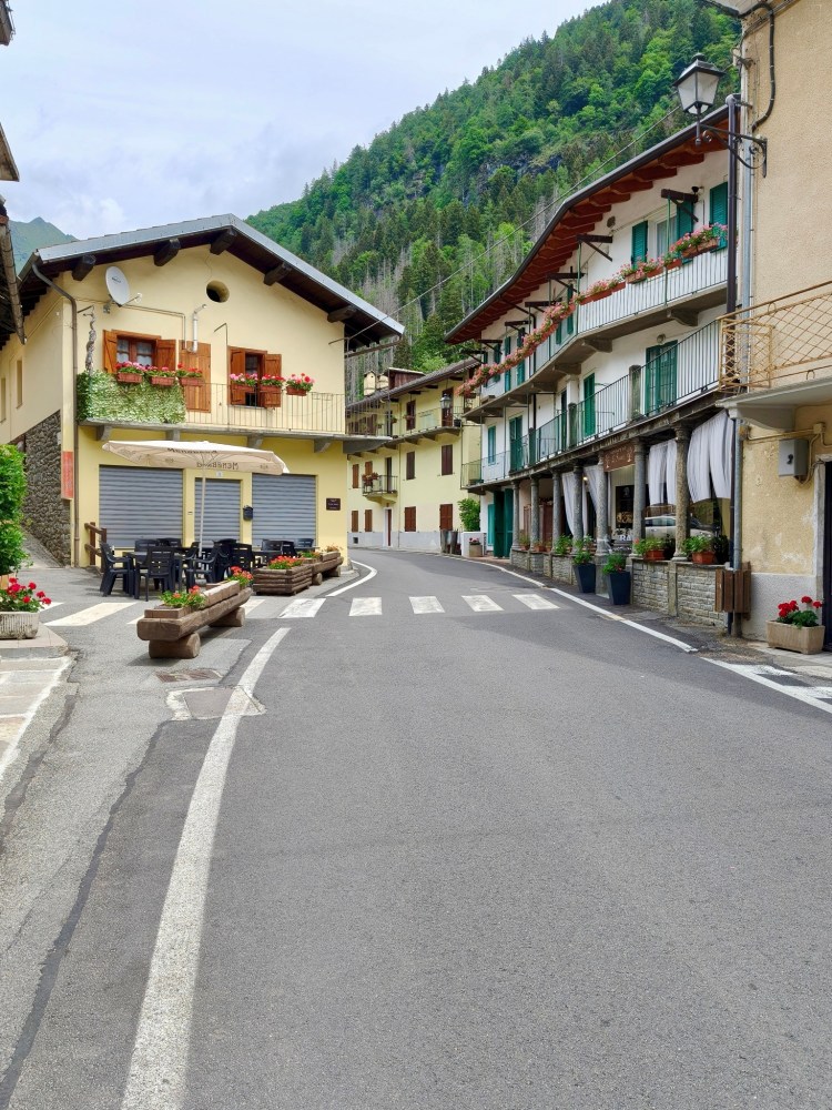Una strada tranquilla in un villaggio di montagna con case colorate e fiori nelle fioriere.